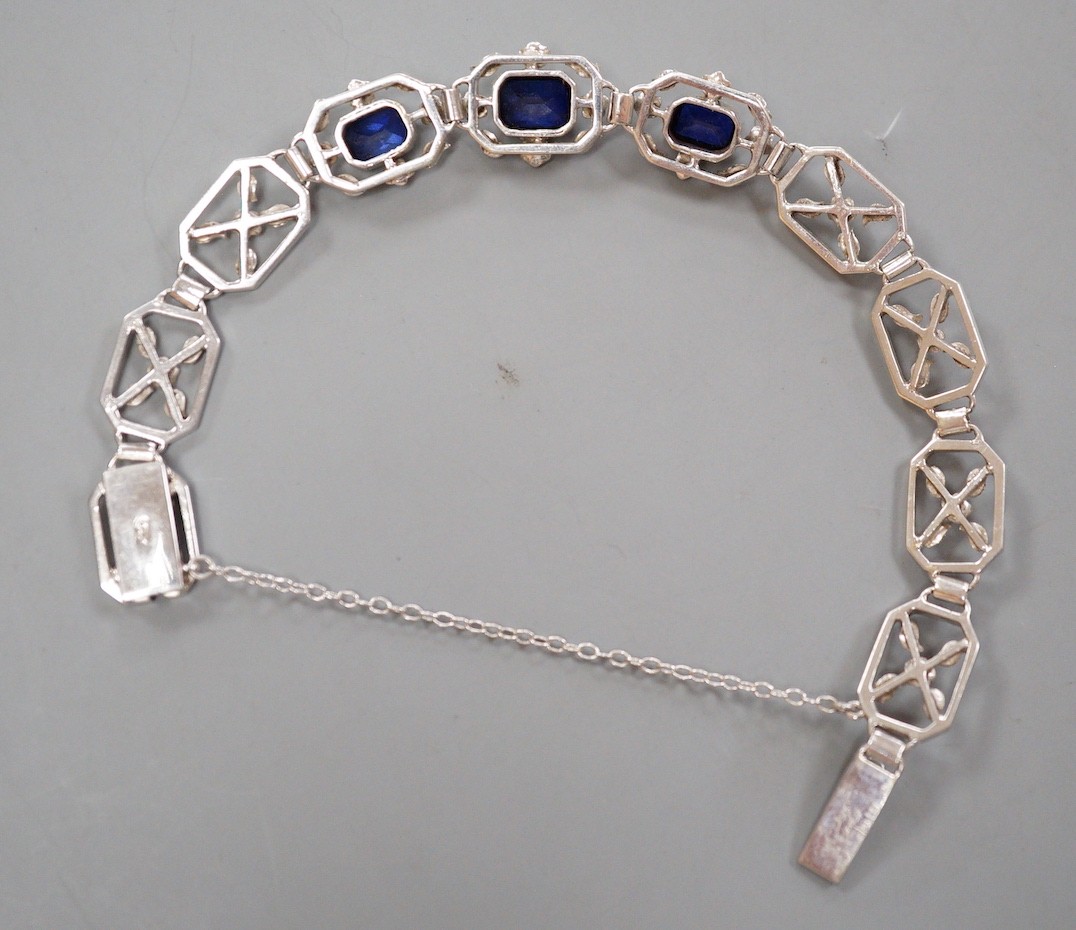 A modern 9ct white metal and three stone emerald cut synthetic sapphire set pierced link bracelet, approx. 18cm, gross weight 16.7 grams.